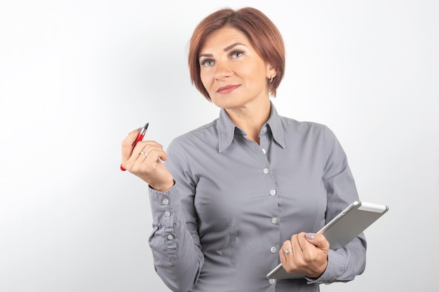 Mooi jong zakenmeisje met een rode pen en een tablet in handen op een witte achtergrond