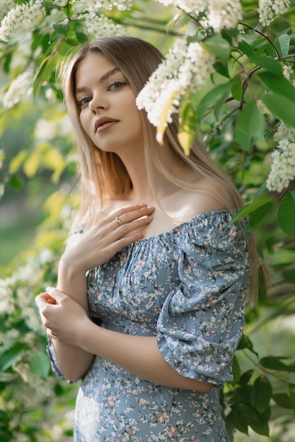 Mooi Kaukasisch meisje staat in een jurk in de buurt van een bloeiende boom