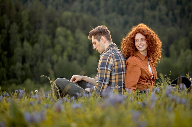 Mooi Kaukasisch paar zit op gras te ontspannen op het platteland in contemplatie genietend van de natuur in cas...