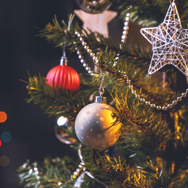 Mooi kerstdecorconcept, kerstbal die aan de kerstboom hangt met sprankelende lichte vlek, wazige donkere zwarte achtergrond, macrodetail, close-up.