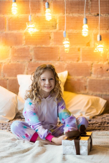 Foto mooi kind in pyjama met een kerstcadeau