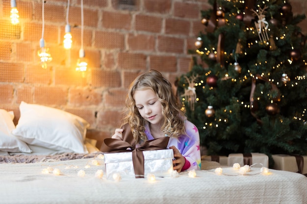 Mooi kind in pyjama met een kerstcadeau