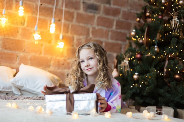 Mooi kind in pyjama met een kerstcadeau