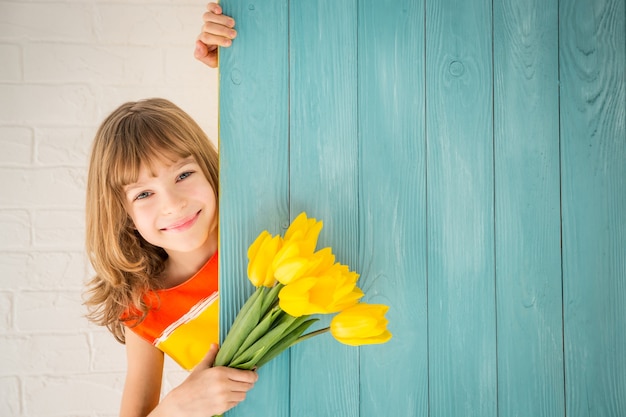 Mooi kind met boeket bloemen verstopt achter houten achtergrond Moederdag