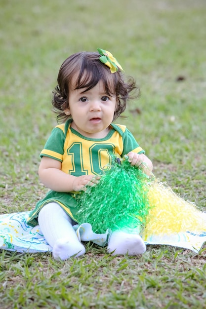 Mooi kind van het Braziliaanse voetbalteam in een park, gekleed in groen en geel