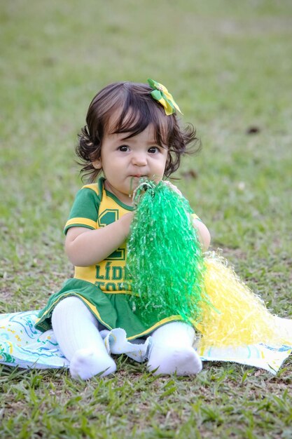 Mooi kind van het Braziliaanse voetbalteam in een park, gekleed in groen en geel