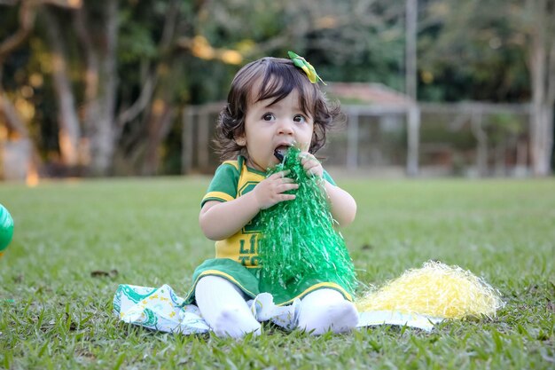 Mooi kind van het Braziliaanse voetbalteam in een park, gekleed in groen en geel