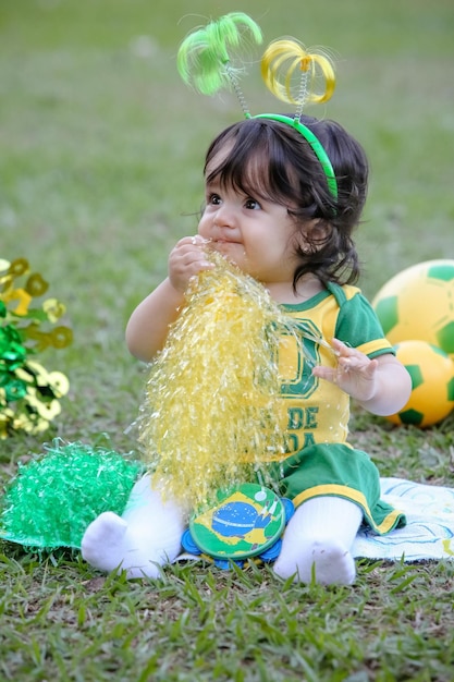 Mooi kind van het Braziliaanse voetbalteam in een park, gekleed in groen en geel