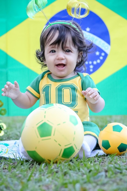 Mooi kind van het Braziliaanse voetbalteam in een park, gekleed in groen en geel