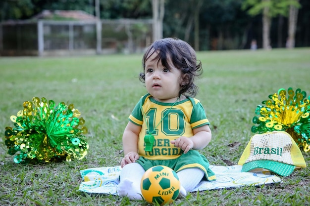 Mooi kind van het braziliaanse voetbalteam in een park, gekleed in groen en geel