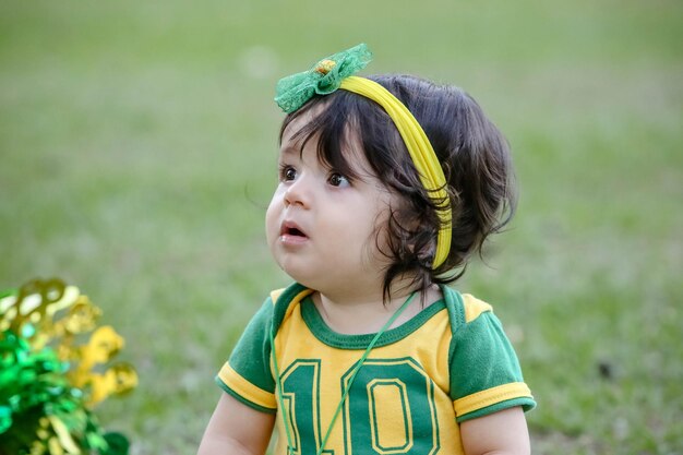 Mooi kind van het braziliaanse voetbalteam in een park, gekleed in groen en geel