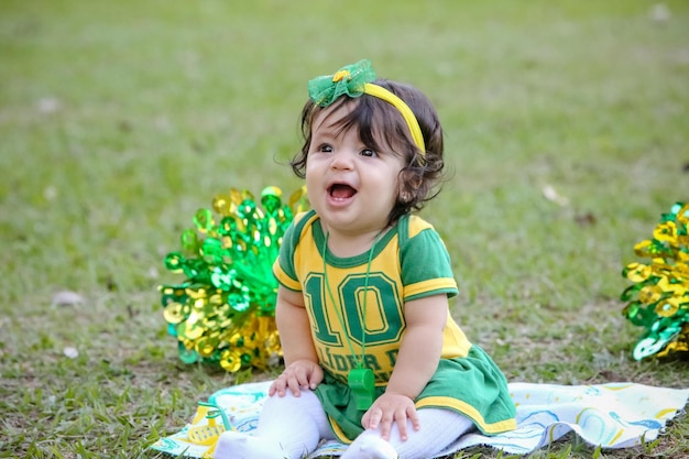 Mooi kind van het Braziliaanse voetbalteam in een park, gekleed in groen en geel