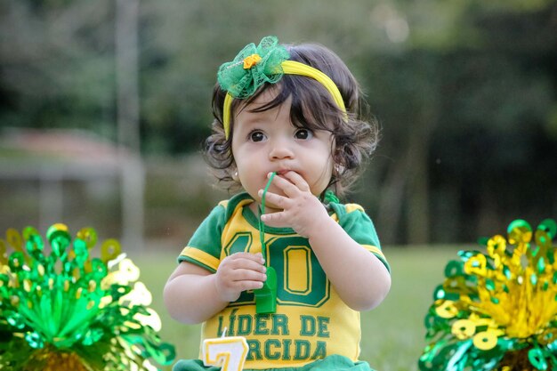 Mooi kind van het Braziliaanse voetbalteam in een park, gekleed in groen en geel