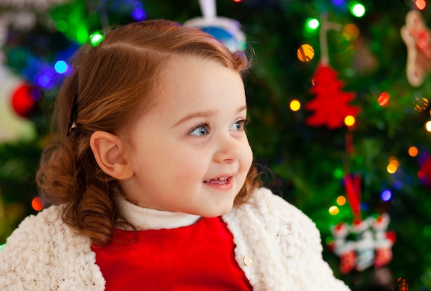 Mooi klein kind in de buurt van de kerstboom.