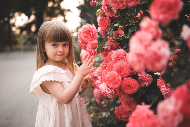 Mooi klein kindmeisje met bloeiende roze bloemen in park buitenshuis