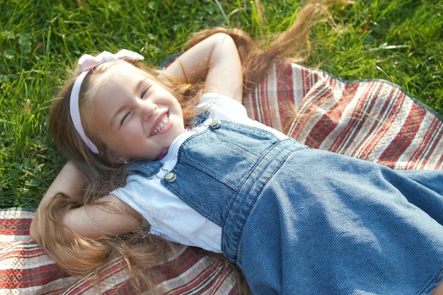 Foto mooi klein kindmeisje met gesloten ogen die in de zomer op groen gras liggen en een dutje doen.