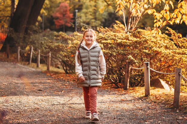 Mooi klein meisje dat in herfstpark rust