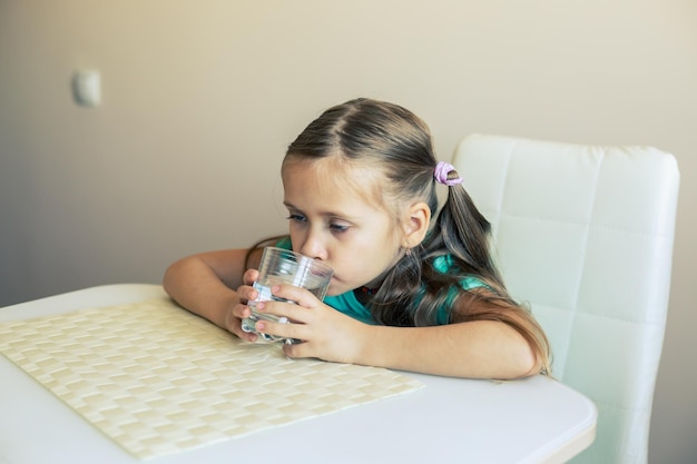 Mooi klein meisje drinkt schoon water uit een transparant glas