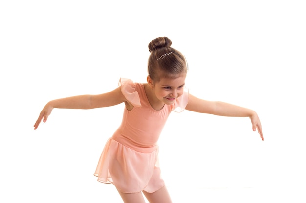 Mooi klein meisje in roze jurk dansen op een witte achtergrond in studio