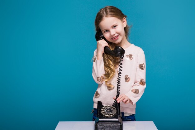 Mooi, klein meisje in trui met donkerbruin haar heeft een telefoongesprek