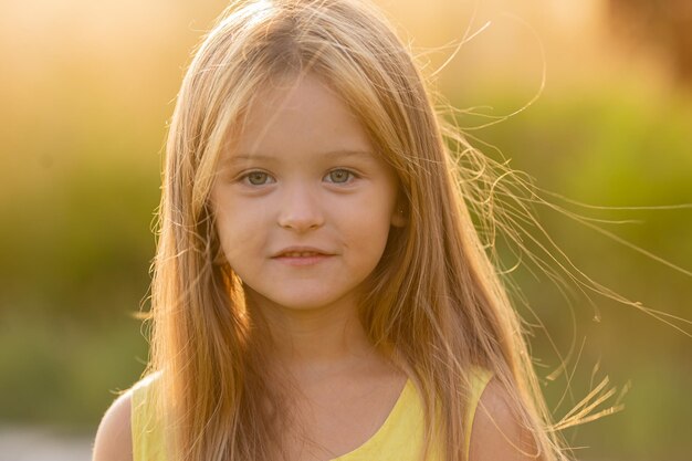 Mooi klein meisje met lang blond haar loopt bij zonsondergang in het stadspark in de zomer