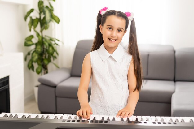 mooi klein meisje pianospelen in lichte kamer.