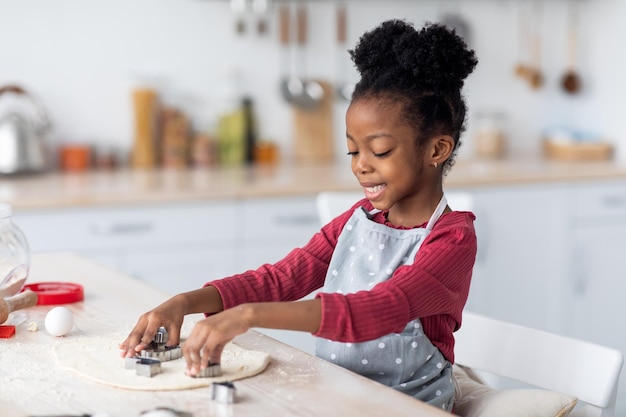 Mooi klein zwart meisje dat koekjes maakt voor haar familie