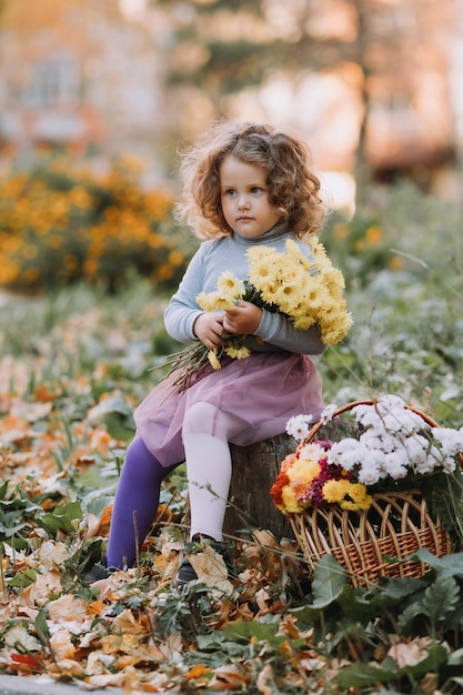 mooi krullend meisje in blauw shirt in park met bloemen in herfsttijd herfst gezondheidskaart
