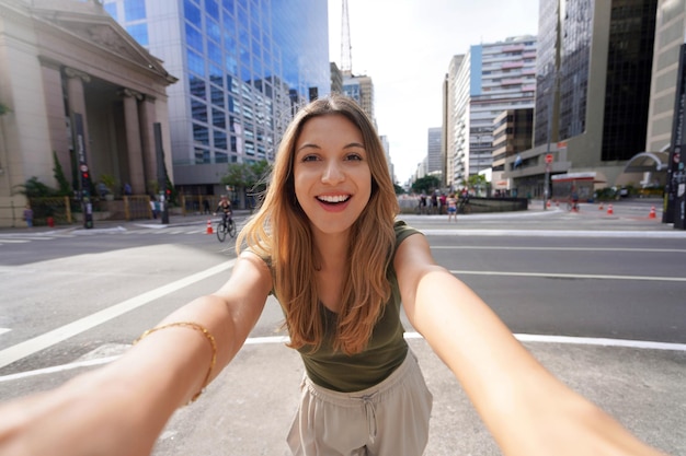 Foto mooi lachend meisje maakt zelfportret op de paulista avenue sao paulo, brazilië