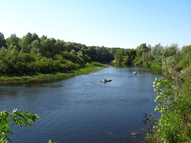 Mooi landschap met rivier en kano met mensen erop.