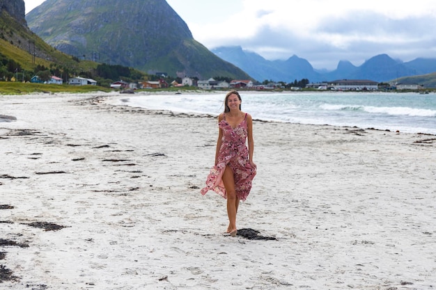 mooi langharig meisje in een jurk loopt langs het beroemde rambergstrand (rambergstranda), noorwegen