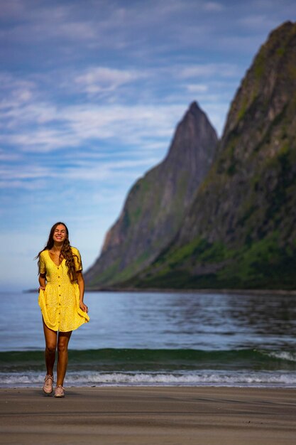 mooi langharig meisje in gele jurk loopt op het beroemde strand ersfjordstranda, senja, noorwegen