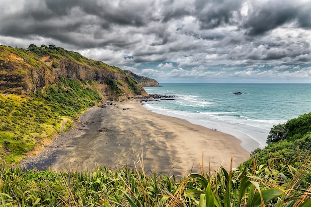 Mooi leeg zwart zandstrand bij Maori-baai dichtbij Muriwai-strand, Noordereiland, Nieuw Zeeland