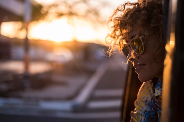 mooi licht en jonge vrouw met krullend haar portret met zonsonderganglicht op gezicht en zonnebril