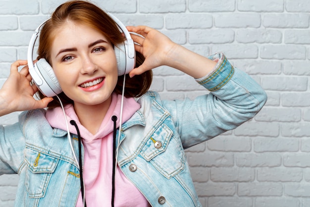 Mooi manier koel meisje dat aan muziek in hoofdtelefoons luistert