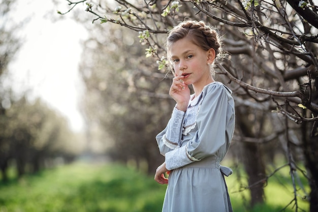 Mooi meisje 6-7 jaar oud poseren in de tuin. pasen. geniet van lente en warmte. prachtige lentetuin. gelukkige jeugd, vrede en geluk concept. aromatische bloesem en retro vintage.