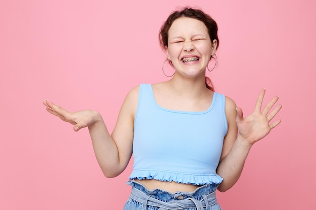 Mooi meisje blauw t-shirt handgebaren emotie roze achtergrond ongewijzigd