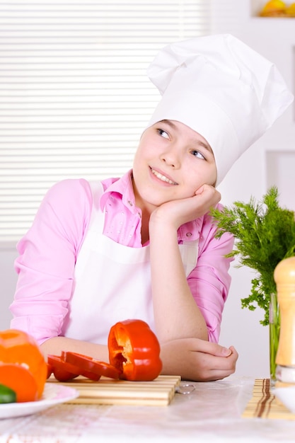 Mooi meisje dat chef-kokuniform draagt met groenten