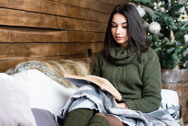 Mooi meisje dat een boek in een Kerstmisatmosfeer leest