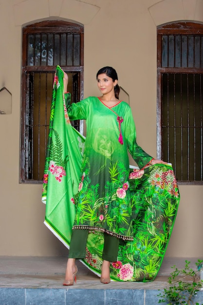 Mooi meisje dat een groene bloemenjurk draagt en Dupatta vasthoudt met een houding voor mode-shoot