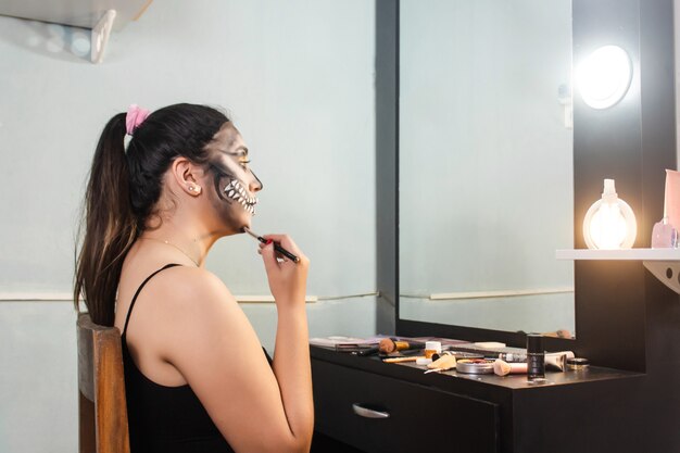 Mooi meisje dat haar Halloween-make-up in haar kamer vervaagt.