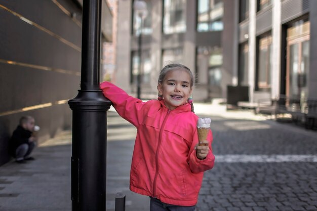 Mooi meisje dat ijs eet op straat over stedelijke achtergrond, grappig snoepkind buiten de levensstijl