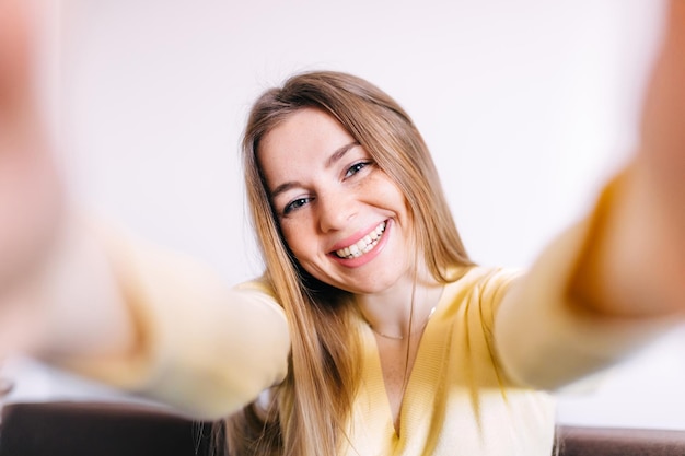 Mooi meisje dat lacht neemt selfie thuis