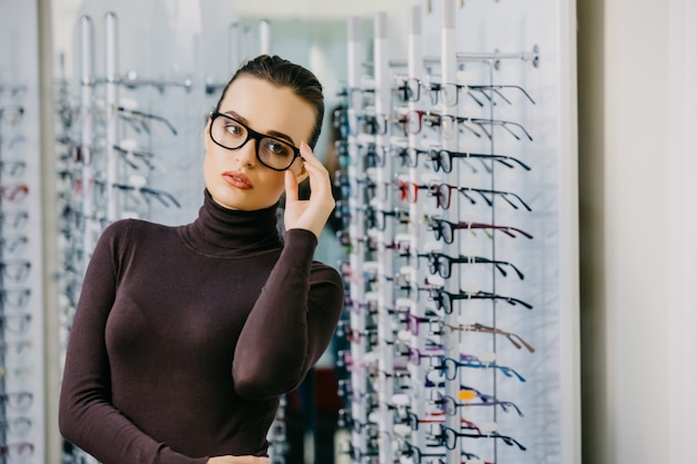 Mooi meisje die glazen in opticienwinkel dragen.