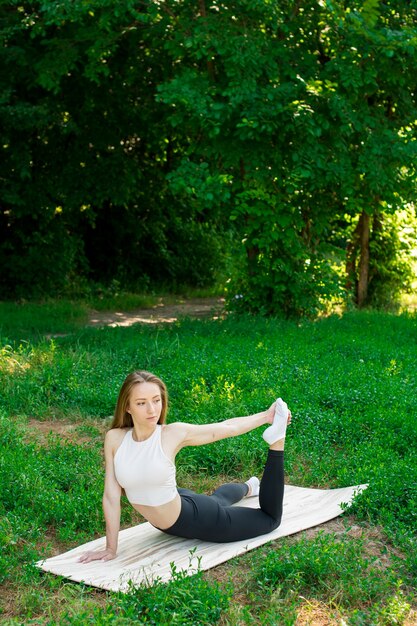 Mooi meisje doet zich het uitrekken na de training op de mat in de natuur