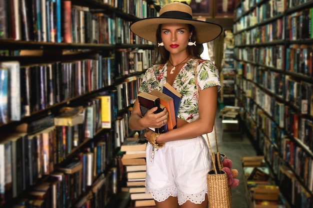 Mooi meisje draagt stijlvolle outfit op zoek naar interessant boek in de kleine vintage boekhandel