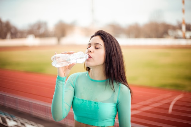 Mooi meisje drinkt water uit een fles na sporttraining