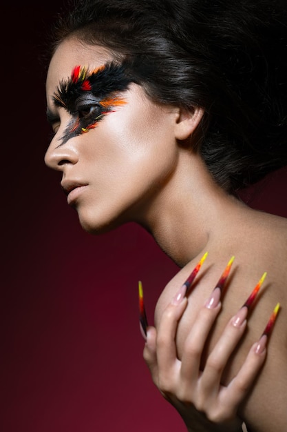 Mooi meisje in beeld van Phoenix vogel met creatieve make-up en lange nagels Manicure ontwerp schoonheid gezicht