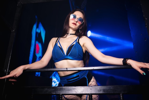 Mooi meisje in blauwe en zwarte lingerie poses op het podium van een nachtclub kijkend naar de camera Party concept