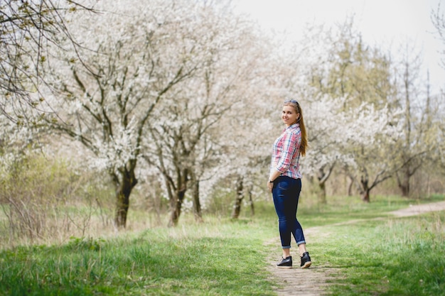 Mooi meisje in bloeiende bomen in het vroege voorjaar. Felle zon en natuur